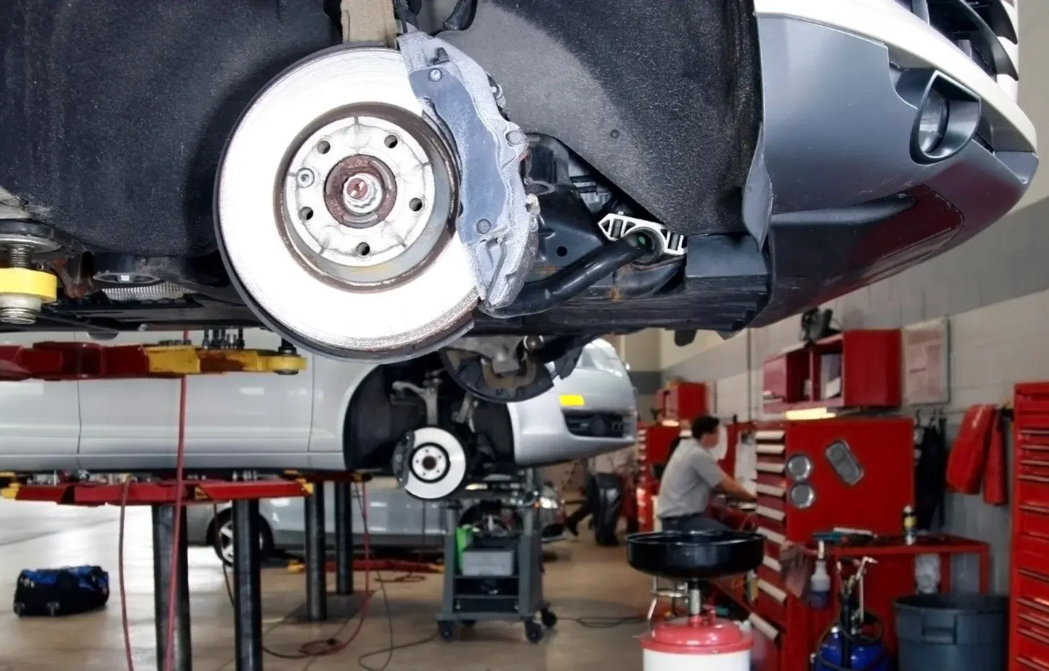 Vehicle on lift in a busy workshop — GuniWheel helping move vehicles off lifts instantly