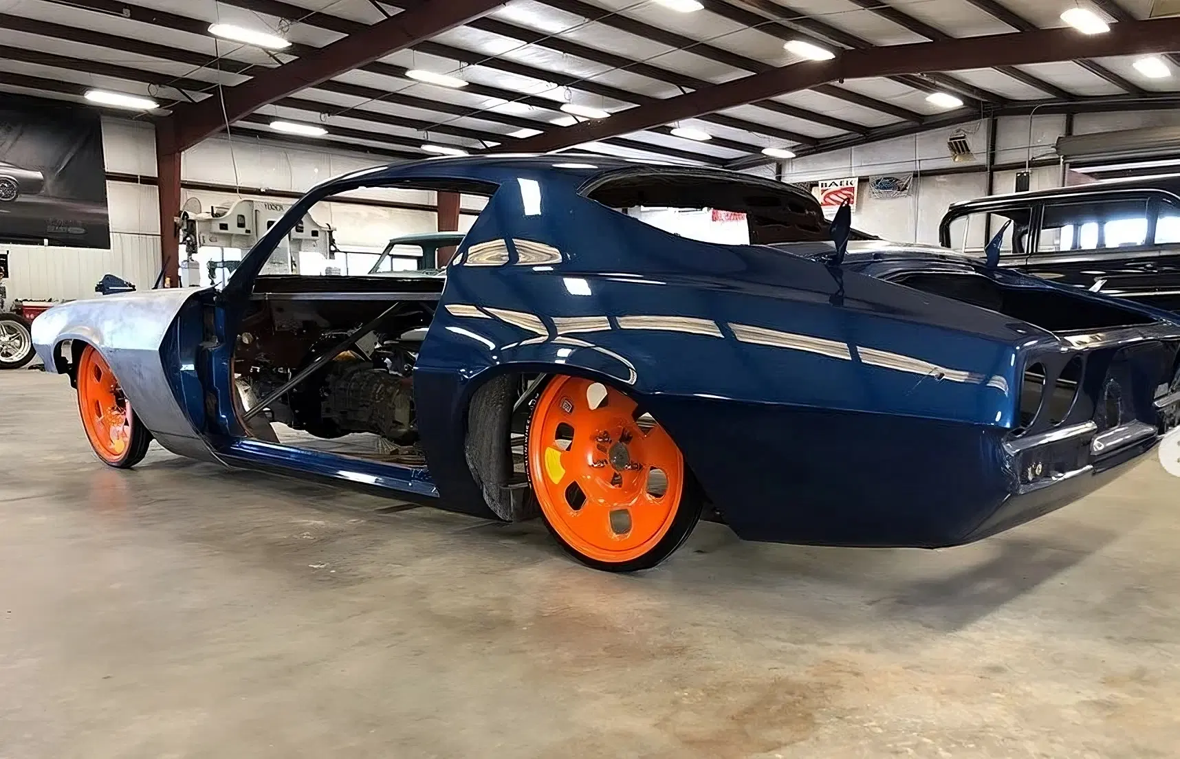 Blue classic car fitted with orange GuniWheel universal wheel system in a workshop